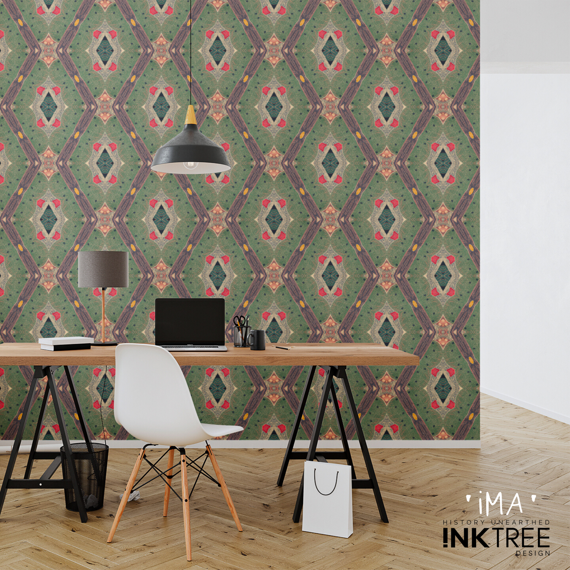 A room with a gold, black, green, red and white oriental looking pattern wall paper. With a white wall adjacent to it.  A black and white pendant light hanging from the ceiling, a wood desk with black legs with a black shaded desk lamp with a wood stand, a laptop computer, a black mug, scissors, note pad and books on the desk.  There's a white chair with wood legs, a black wire waste basket, a screwed up paper ball and a white paper shopping bag with black rope handles on a parquetry wood floor. 