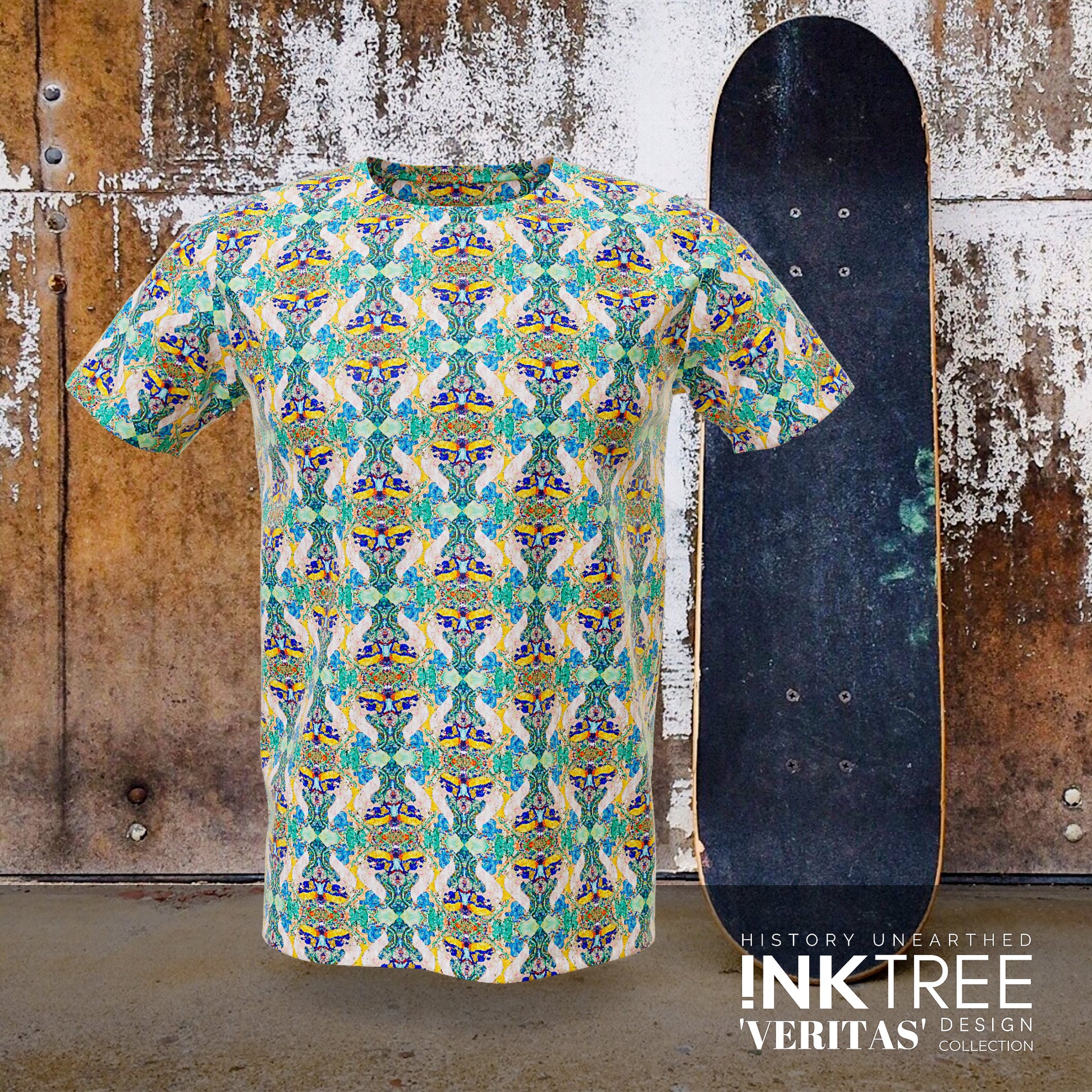 A tshirt with a green, blue and gold pattern.with a skateboard and rusty wall background.