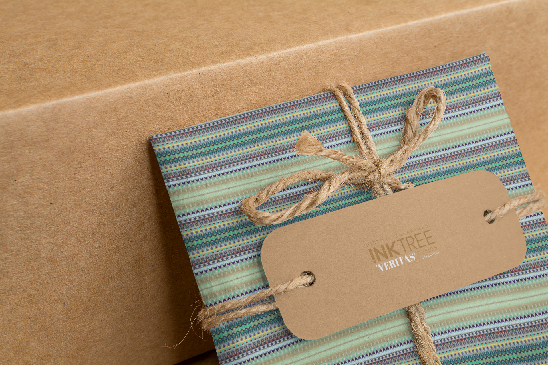 A wrapped present with brown paper in the background.  Tied with brown twine and brown tag, with blue and black and green pattern.
