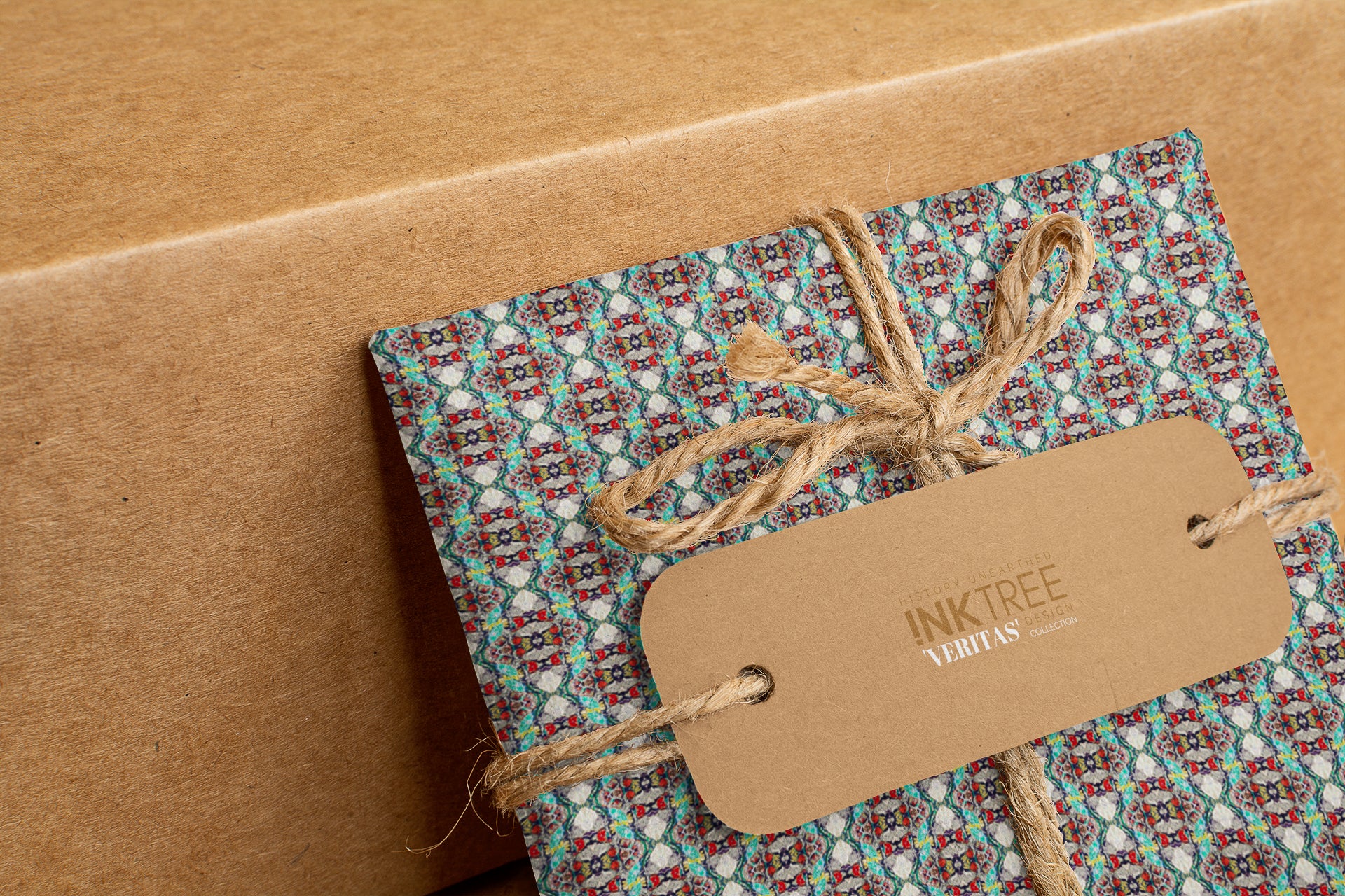 A wrapped present with brown paper in the background.  Tied with brown twine and brown tag, with blue, red and green pattern.
