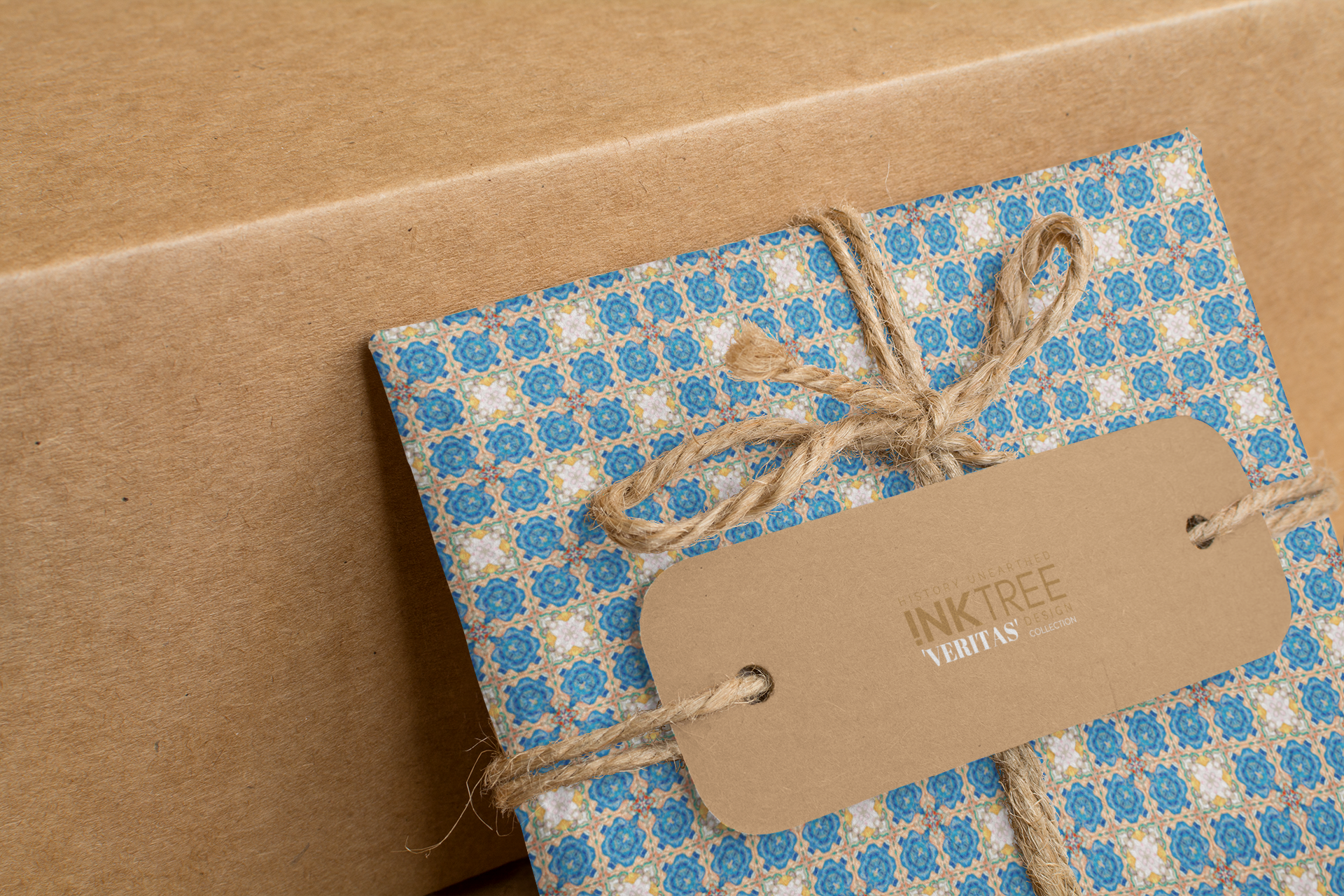A wrapped present with brown paper in the background.  Tied with brown twine and brown tag, with blue and yellow pattern.