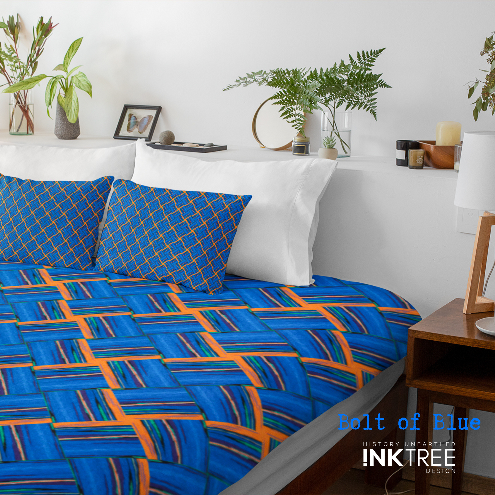A doona cover and front pillows with an orange, white, black, blue and green square pattern on a bed with a white wall, white pillows and white backboard background. There is a lamp with a white shade and wood base and plants and a small round metal mirror on the back board. There is also a bolt of blue, history unearthed ink tree design logo in the bottom right hand corner on it.